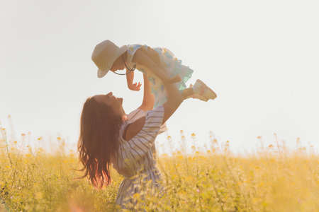 beautiful young mother and her daughter having fun at the wheat field.の写真素材