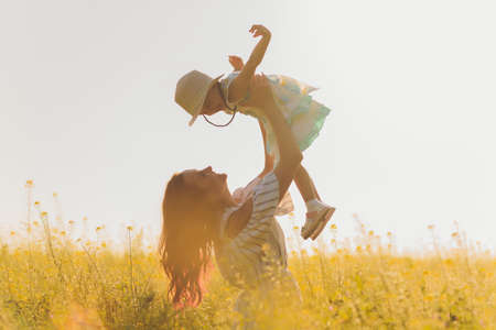 beautiful young mother and her daughter having fun at the wheat field.の写真素材