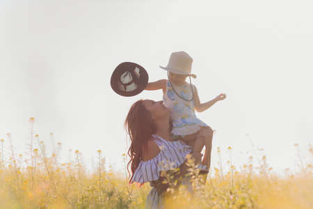 beautiful young mother and her daughter having fun at the wheat field.の写真素材