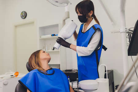 Dentist working with dental polymerization lamp in oral cavity.の写真素材