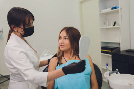 The patient admires her smile looking at the mirror.の写真素材