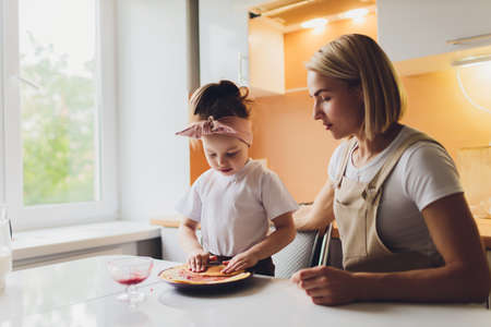 Portrait of an adorable mother and daughter preparing a daughter together in the kitchen.の写真素材