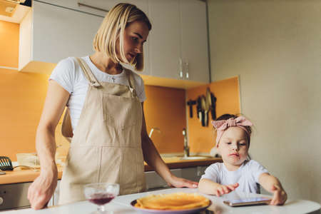Girl eating at the table playing on the phone.の写真素材