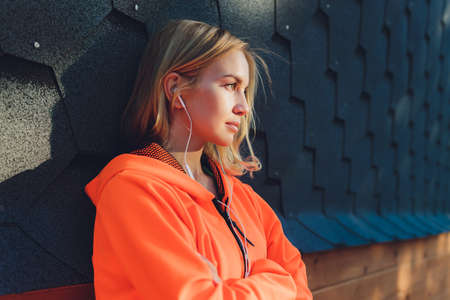 Young woman relaxing outdoors on a modern bridge while listening to music.の写真素材