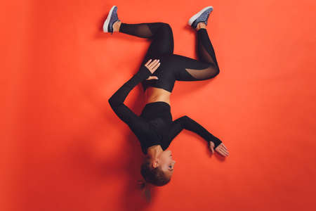 Portrait of a beautiful fit young sportswoman standing over red background, pointing at copy space.
