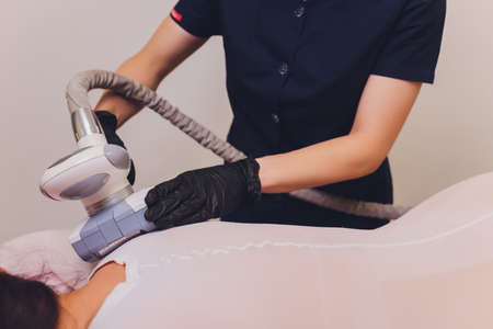 Parts of female body in special white suit having anti cellulite massage with spa apparatus.の写真素材