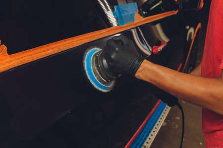 Hands with Auto polisher. Car repair service.