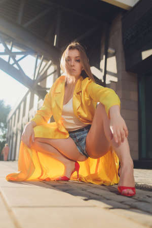 Displaying fashion tendencies. Dark-haired attractive woman posturing in bright yellow fluffy cloak.の写真素材