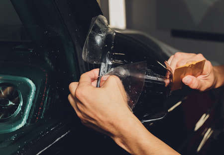Close up of paint protection film installation on side mirror of modern luxury car. PPF is polyurethane film applied to painted of car to protect the paint from stone chips, bug splatter, and abrasionの写真素材