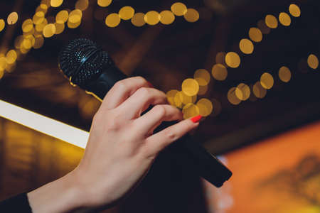 Microphone and female singer close up. Woman singing into a microphone, holding mic with hands.の写真素材