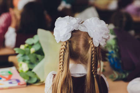 Hair braided in two braids with white bows hairstyle schoolgirl holiday.の写真素材