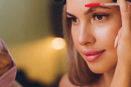 Young woman having professional eyebrow correction procedure in beauty salon.