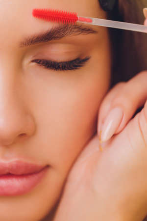 Young woman having professional eyebrow correction procedure in beauty salon.の写真素材