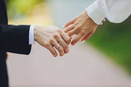 The groom holds the brides hand at the wedding ceremony. Hold hands and walk together. Confidence. On the bride s hand is a white gold ring with black diamonds.の写真素材