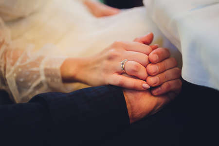 The groom holds the brides hand at the wedding ceremony. Hold hands and walk together. Confidence. On the bride s hand is a white gold ring with black diamonds.の写真素材