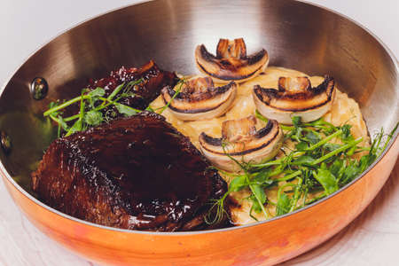 A grilled rib steak with sauteed mushrooms and mashed potatoes infused with savory herbs.の写真素材