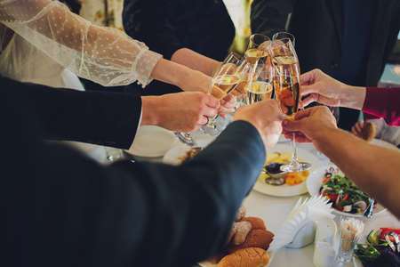 Close up shot of group of people clinking glasses with wine or champagne in front of bokeh background. older people hands.の写真素材