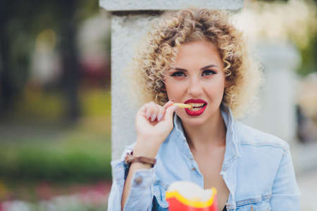 Young Woman Eating A French Fries Street food.の写真素材