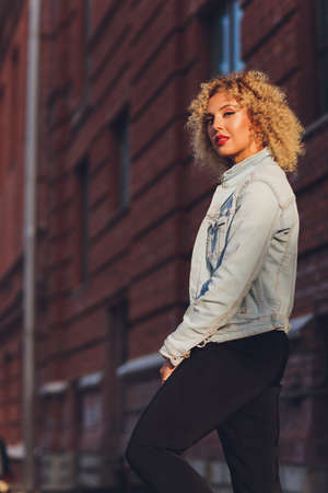 Beautiful young Caucasian girl with curly hair outdoors.の写真素材