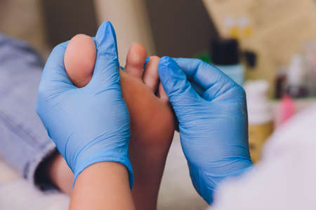Therapist hands in protective gloves massaging womans feet.の写真素材