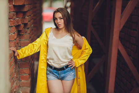 Displaying fashion tendencies. Dark-haired attractive woman posturing in bright yellow fluffy cloak.の写真素材