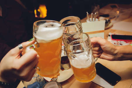 Close up shot of group of people clinking glasses with beer in front of bokeh background. older people hands.の写真素材