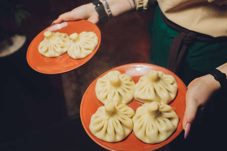 Georgian khinkali tray in hands close up.の写真素材
