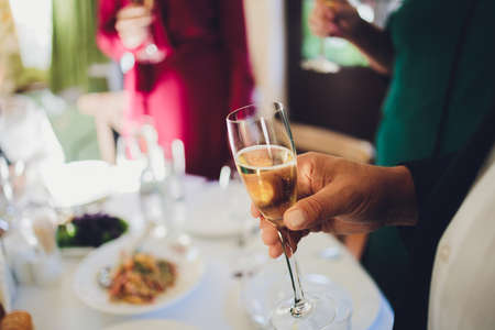Close up shot of group of people clinking glasses with wine or champagne in front of bokeh background. older people hands.の写真素材
