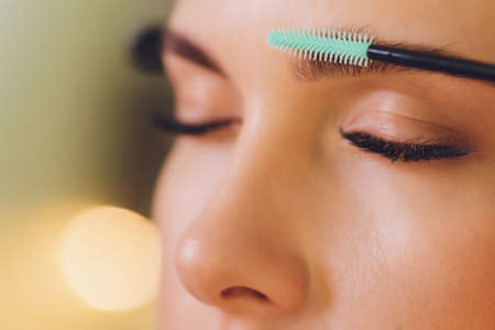 Young woman having professional eyebrow correction procedure in beauty salon.の写真素材