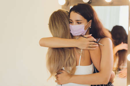 New normal. Two women together with medical protective facial facemask. Girls is hugging at the street. Coronavirus and quarantine concept outdoors. Violation of social distancing.の写真素材