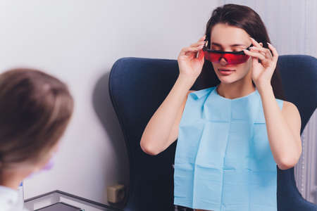 Close-up portrait of a female patient visiting dentist for teeth whitening in clinic,Teeth whitening procedure.の写真素材