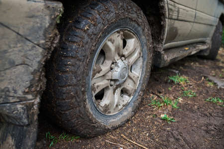 Wheel closeup in a countryside landscape with a muddy road.