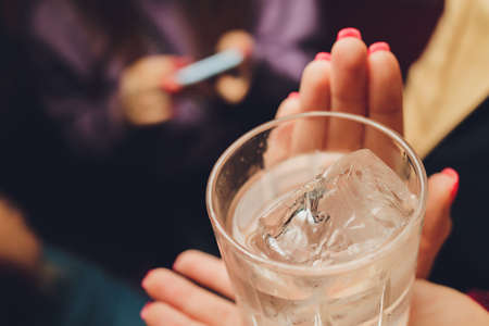 Female hands holding a clear glass of water. Slime body on background.の写真素材