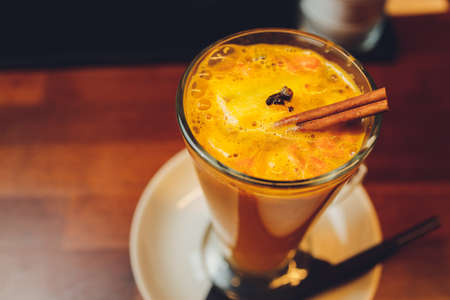 Glass of orange cocktail decorated with lemon at bar counter background.