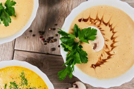 Different kinds of soups - pumpkin soup, cheese cream-soup and mushroom cream-soup on the table.の写真素材