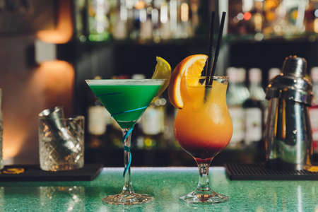 Green cocktail in modern glass on bar background.