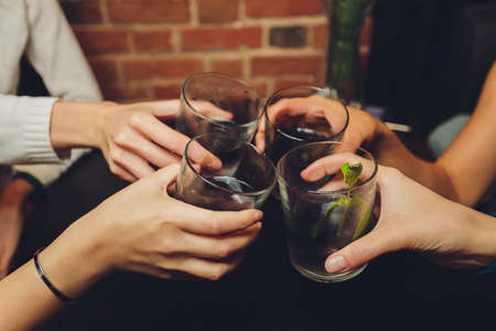Close up shot of group of people clinking glasses with wine or champagne in front of bokeh background. older people hands.の写真素材