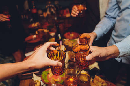 Close up shot of group of people clinking glasses with wine or champagne in front of bokeh background. older people hands.の写真素材