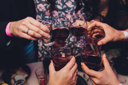 Close up shot of group of people clinking glasses with wine or champagne in front of bokeh background. older people hands.の写真素材