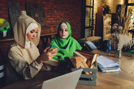 Young muslim asian female designer using graphics tablet while working with computer at studio or office.の写真素材