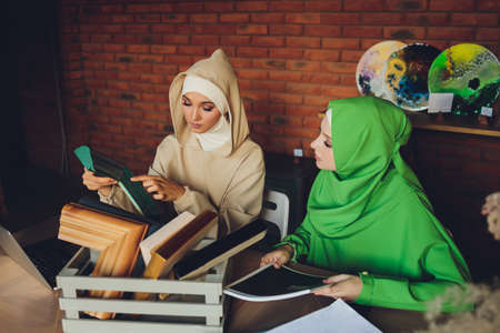 Young muslim asian female designer using graphics tablet while working with computer at studio or office.の写真素材