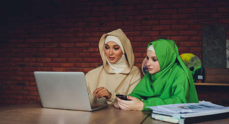 Young muslim asian female designer using graphics tablet while working with computer at studio or office.の写真素材
