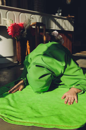 Muslim woman in hijab praying on mat indoors.の写真素材