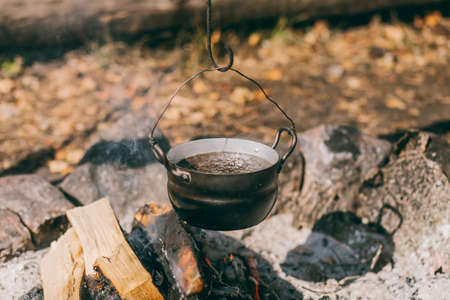 Hiking pot, Bowler in the bonfire. soup boils in cauldron at the stake. Traveling, tourism, picnic...