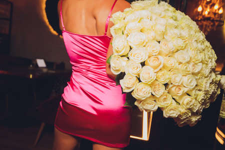 attractive young girl holding a large basket with white roses close up.
