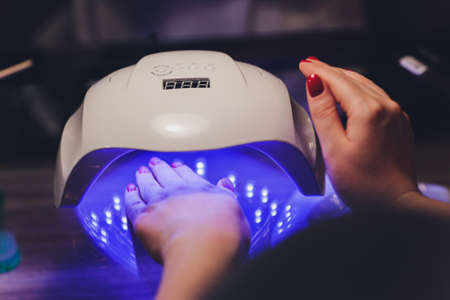 Close-up of beautician applying colorful varnish. Applying nail polish on nails with a brush for...