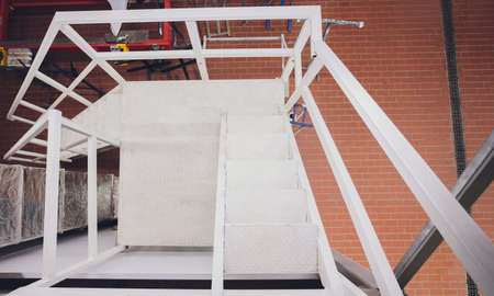 Fire escape ladder or emergency exit with steel staircase on wall of modern industrial building.