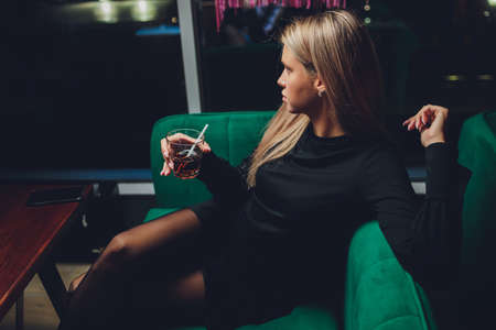 Happy woman at a party smiling and holding a cocktail drink.