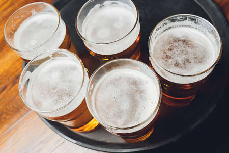 Waiter serving glasses of cold beer on the tray.