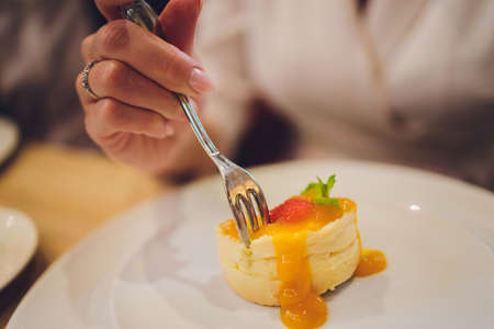 Three berries cheesecake style on white plate with hand use the fork to eat.